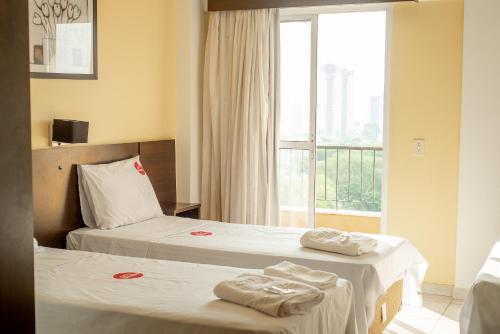 duas camas num quarto de hotel com toalhas em City Bauru Reserve Agora em Bauru