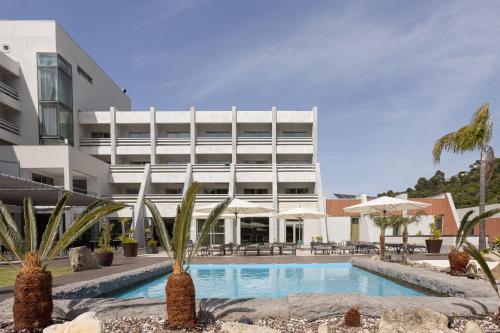 a hotel with a swimming pool in front of a building at Hotel Porta do Sol Conference & SPA in Caminha