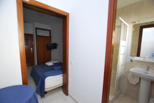 a bedroom with a bed and a bathroom with a sink at Hotel Tres Leones in Vilassar de Mar
