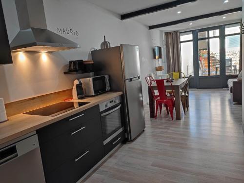 une cuisine avec un réfrigérateur en acier inoxydable et une table dans l'établissement Le Gabin Moderne Loft, à Carcassonne