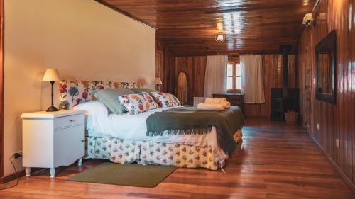 ein Schlafzimmer mit einem Bett in einem Zimmer mit Holzböden in der Unterkunft Hostería Villarino in San Martín de los Andes