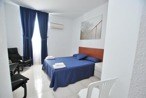 een slaapkamer met een blauw bed en stoelen. bij Hotel Tres Leones in Vilassar de Mar