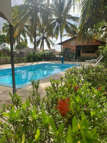a swimming pool with palm trees in the background at Chalé com 5 suítes em Maxaranguape in Maxaranguape