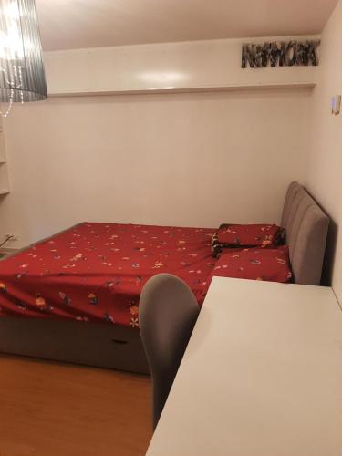 une petite chambre avec un lit avec une couverture rouge dans l'établissement Maison d'ozoir, à Ozoir-la-Ferrière
