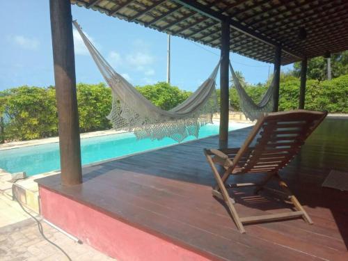 a hammock on a deck next to a swimming pool at A janela do amanhecer in Maxaranguape