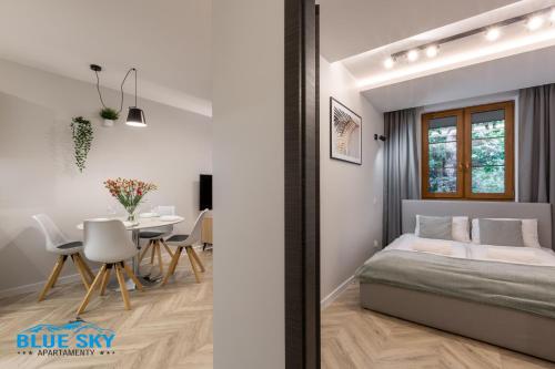 a bedroom with a bed and a dining room with a table at Apartamenty BlueSky - Nad Łomnicą 14 - centrum Karpacza, blisko deptaka in Karpacz