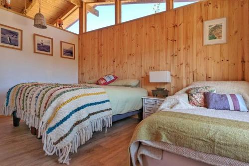 2 camas en una habitación con paredes de madera en ArboLodge, en Vichuquén