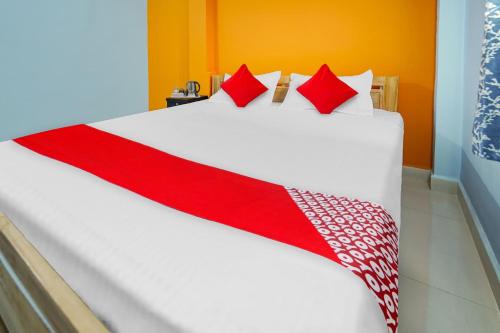 Una gran cama blanca con almohadas rojas. en Flagship Youngsky, en Gulzārbāgh