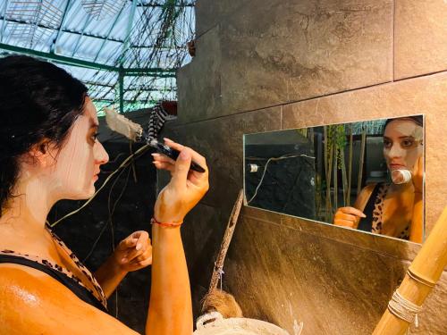 una mujer cepillándose el pelo delante de un espejo en Ecopark Hosteria Puyo, en Puyo