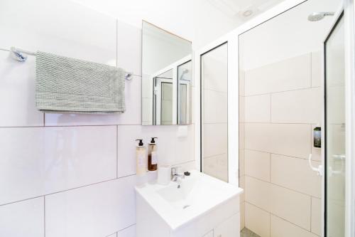 La salle de bains blanche est pourvue d'un lavabo et d'un miroir. dans l'établissement Casa na Ilha III, à Funchal
