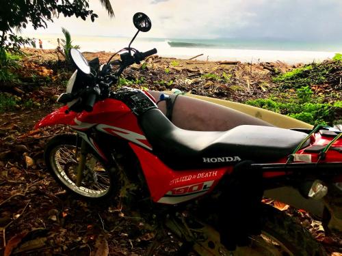 a red motorcycle parked on the side of a beach at Brahman Bungalows on Pavones Point in Pavones