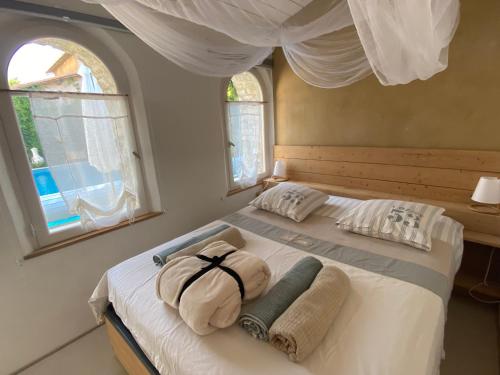 um quarto com uma cama com duas almofadas e duas janelas em Le Patio aux Oiseaux em La Ciotat