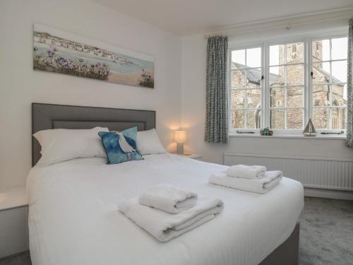 a bedroom with a large white bed with towels on it at Quayside in Dartmouth