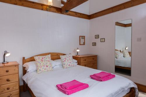 a bedroom with a bed with two towels on it at Halcyon Cottage in Little Torrington