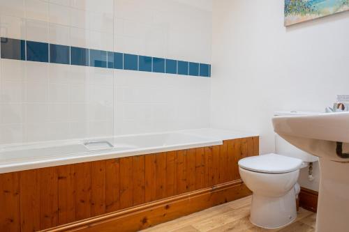 a bathroom with a tub and a toilet and a sink at Tarquol Cottage in Little Torrington