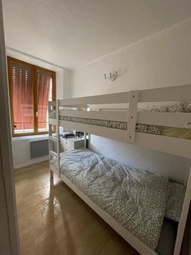 een slaapkamer met 2 stapelbedden en een raam bij Nid douillet proche des Thermes in Bourbonne-les-Bains