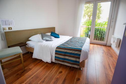 a bedroom with a bed and a large window at Contact Hotel Du Ladhof in Colmar