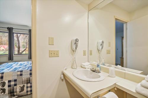 Baño blanco con lavabo y espejo en Cedarbrook Deluxe Two Bedroom Suite with outdoor heated pool 10708, en Killington