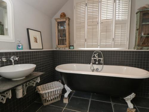 a bathroom with a black and white tub and a sink at Brandeers Long Barn in Malmesbury