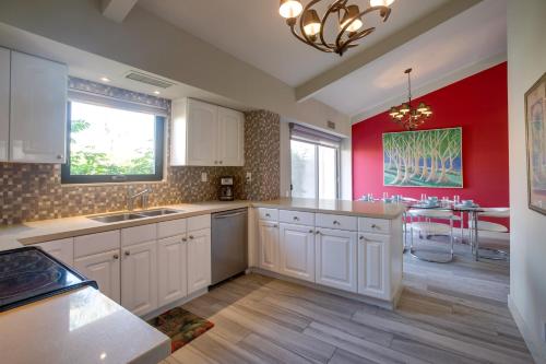 a kitchen with white cabinets and a red wall at Luxe Retreat Rancho Mirage Villa with Pool Access! in Rancho Mirage