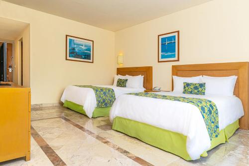 a hotel room with two beds and a television at Krystal Vallarta in Puerto Vallarta