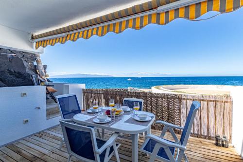 einen Tisch und Stühle auf einem Balkon mit Meerblick in der Unterkunft Oceanfront Oasis by Dream Homes Tenerife in Acantilado de los Gigantes