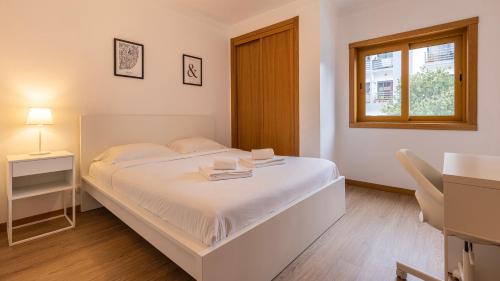 a white bedroom with a bed and a window at 3 Bedroom Oeiras Wonder W/ Balcony by LovelyStay in Oeiras
