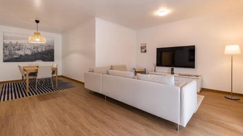 a living room with a white couch and a tv at 3 Bedroom Oeiras Wonder W/ Balcony by LovelyStay in Oeiras