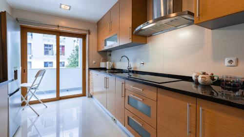a kitchen with wooden cabinets and a large window at 3 Bedroom Oeiras Wonder W/ Balcony by LovelyStay in Oeiras