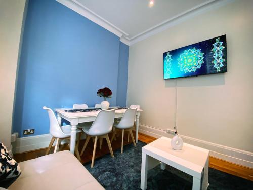 a room with a table and chairs and a tv on the wall at 3-Bedroom Flat Central London, 6 Min Walk from King's Cross Station in London