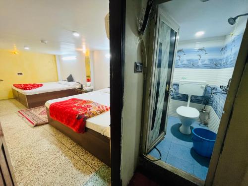 a bedroom with a bed and a bathroom with a toilet at Ganga Guest House in Varanasi