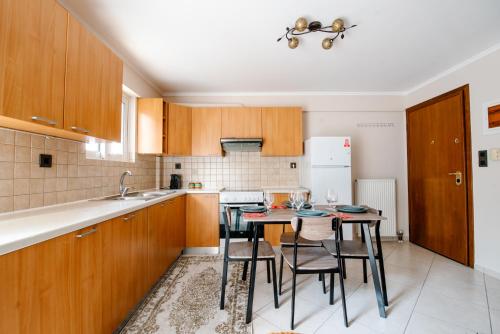 a kitchen with wooden cabinets and a table with chairs at Alexandros Apartments in Paralía Proastíou