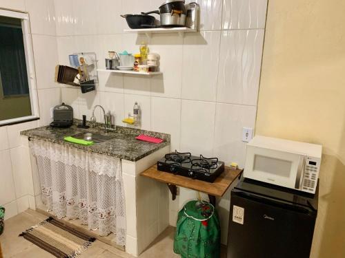 a small kitchen with a sink and a microwave at Casa Pitanga - Abraão - Ilha Grande in Abraão