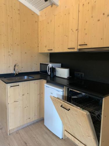 a kitchen with wooden cabinets and a sink and a dishwasher at Càmping Organyà Park in Organyà