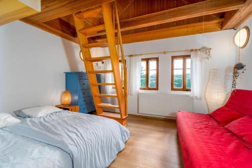 1 dormitorio con cama elevada y sofá rojo en Chaloupka na Kamence en Trutnov