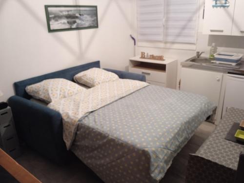 ein kleines Schlafzimmer mit einem Bett und einer Küche in der Unterkunft Capucine 