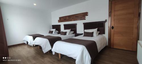 un grupo de 3 camas en una habitación en Hotel y Cabañas Pulegan, en Porvenir