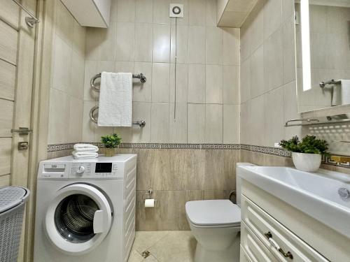 a bathroom with a washing machine and a sink at Студия ПЕНИЕ ПТИЦ в центре Алматы in Almaty