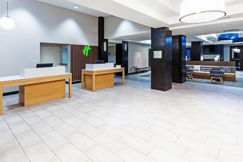 Holiday Inn & Suites Stillwater-University West, an IHG Hotel في ستيلووتر: مكتب فيه مكاتب وكراسي في لوبي