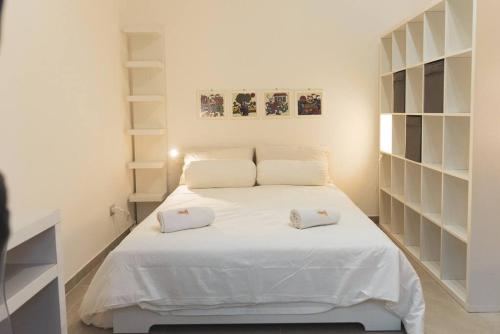 a bedroom with a white bed with two pillows on it at Cas'aPina apartment in Aci Bonaccorsi