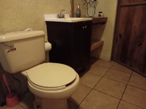 uma casa de banho com um WC branco e um lavatório. em La Troje Cabañas em Tepoztlán