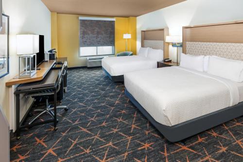 a hotel room with two beds and a desk at Holiday Inn & Suites Stillwater-University West by IHG in Stillwater