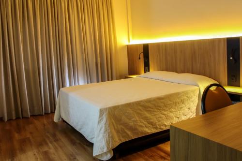 um quarto de hotel com duas camas e uma mesa em Hotel das Videiras em Videira