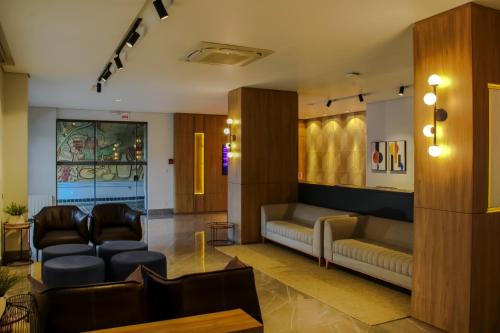 uma sala de espera com sofás e cadeiras no átrio em Hotel das Videiras em Videira