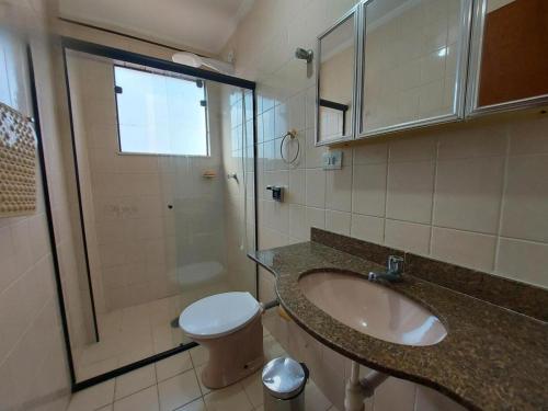 y baño con lavabo, aseo y ducha. en Apartamento - Praia do Tombo, en Guarujá