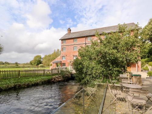 a large red brick building next to a river at The Happy Hut in Christchurch