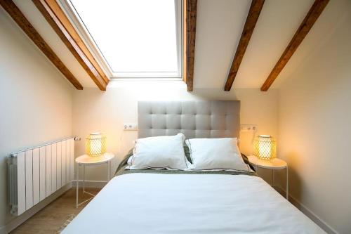 a bedroom with a large bed with two lamps at Designer duplex in the center in Santander