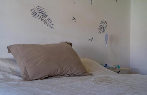 Dormitorio con cama con almohada y hojas en la pared en Casita con parque,a 2 cuadras de la playa en Mar del Plata