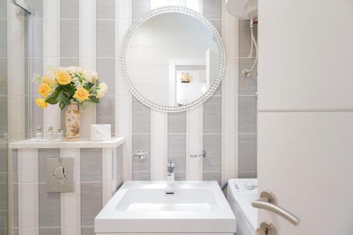 a bathroom with a sink and a mirror and flowers at Villa Capitis in the center-Deluxe Apartment with Swimming Pool in Hvar