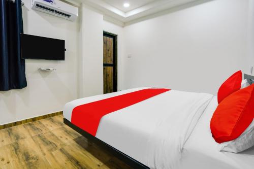 1 dormitorio con 1 cama con almohadas rojas y TV en Super OYO Flagship Hotel White Villa, en Dhantoli